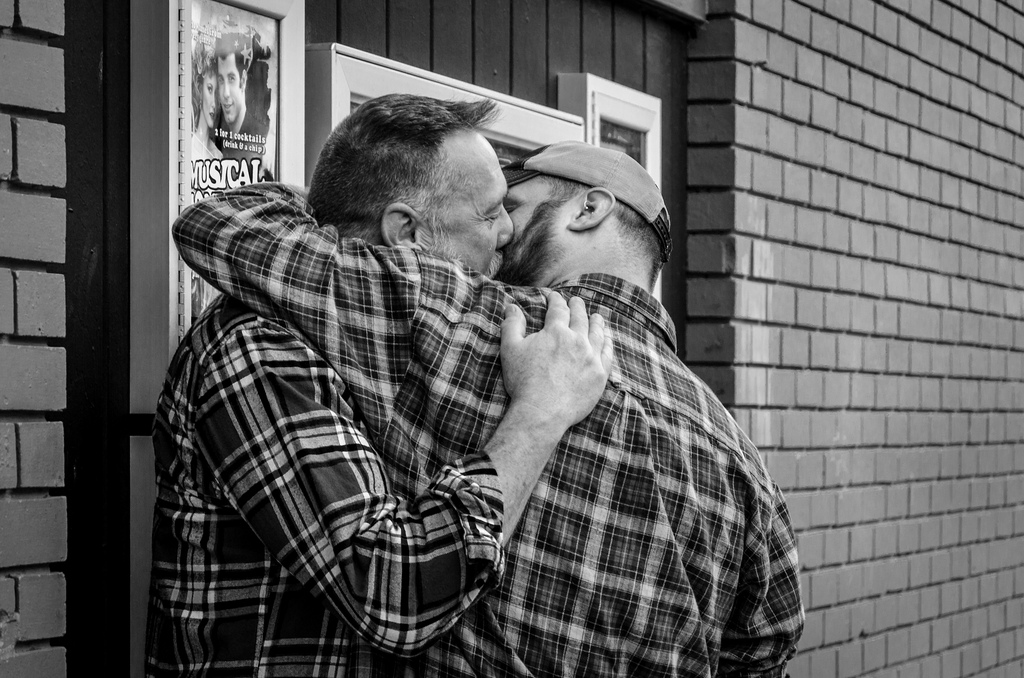 Zwei sich küssende Männer an einer Hauswand