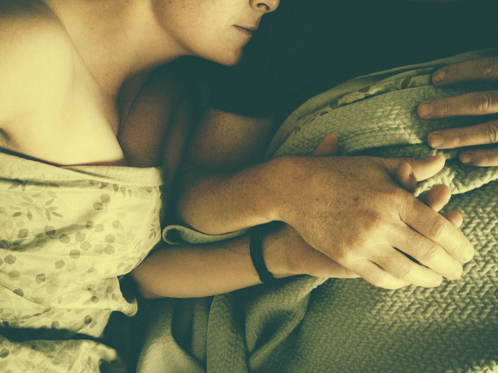 Eine Frau und ein Mann liegen Hände haltend im Bett