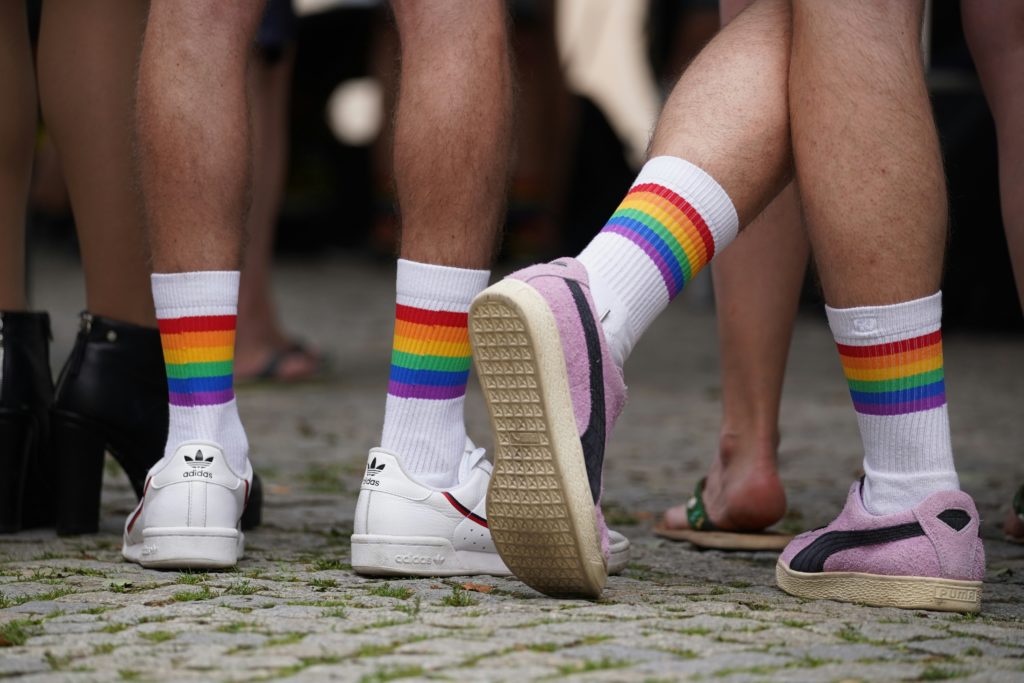 diverse Beine mit Turnschuhen, weißen Socken und Pride Flag Ringeln