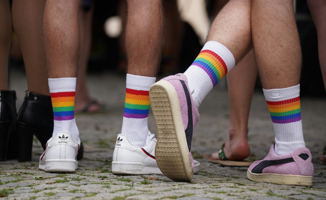 diverse Beine mit Turnschuhen, weißen Socken und Pride Flag Ringeln