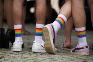 diverse Beine mit Turnschuhen, weißen Socken und Pride Flag Ringeln