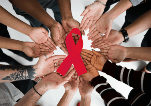 Viele Hände hälten eine Aids-Schleife